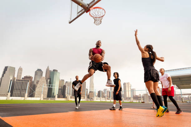 A person in a basketball uniform, jumping to make a slam dunk, showcasing their physical coordination and body control.